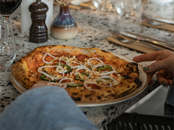 Vedugnsbakad pizza som serveras med tillbehör